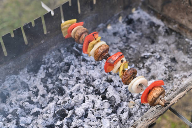 Mushrooms and vegetables are cooked on a skewer on the grill.