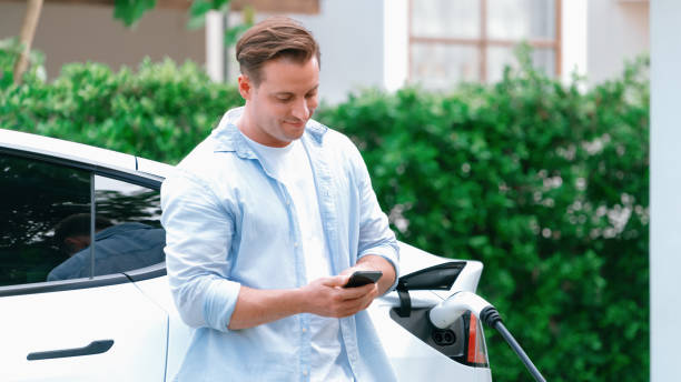 istock Modern eco man recharge EV car at home with phone. Synchronos 2052666126