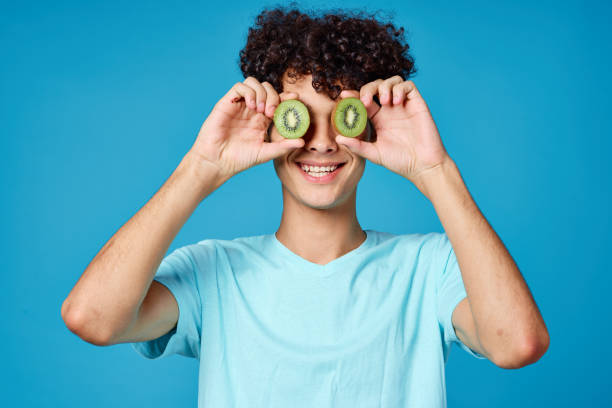 istock Cheerful guy with curly hair kiwi fruit blue background 2052667165