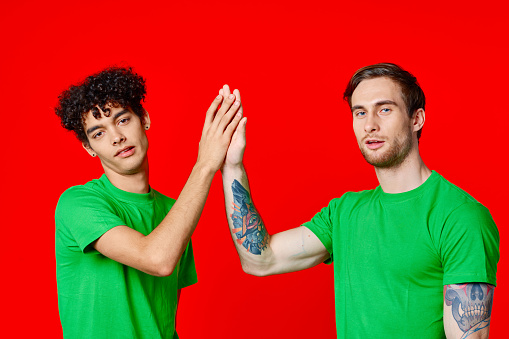 Cheerful friends in green t-shirts gesturing with hands isolated background. High quality photo