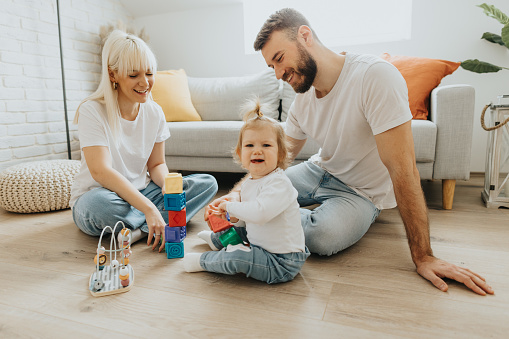 Full length shot of young couple having fun while building toy blocks with their cute little daughter in living room at home