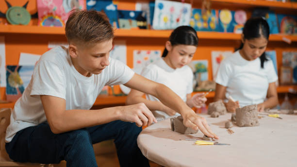 istock Teenager using carving tool working at clay at pottery workshop. Edification. 2052699536