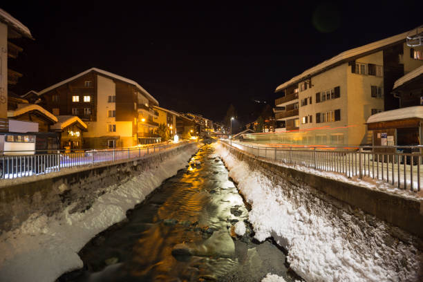 A time lapse shot at night time showing the village of Zermatt glowing orange with the iconic Matterhorn hanging out in the background with clouds across it