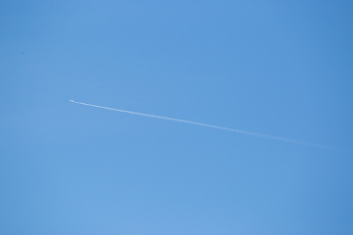 A plane flying through blue skies with condensation trails from the wings