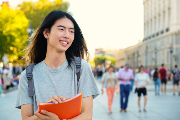 istock Taiwanese male student smiling with a folder and backpack at university campus. 2052776088