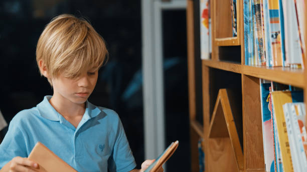 istock Young smart caucasian boy picking from book shelf and reading a book. Erudition. 2052823345