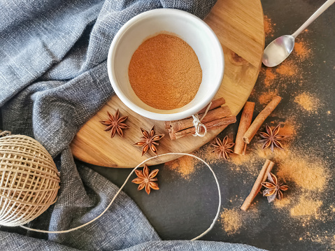 Set up view on table, decorated with dried cinnamon rolls and cinnamon powder inside a bowl, several dried aniseed flowers, rustic fabric cloth...