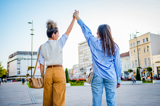 Cheerful young best female friends spending day together in the city