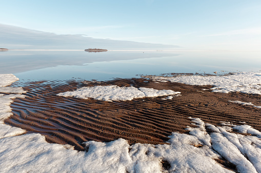 Tranquil spring evening by the calm sea on a sandy beach with still some ice left, Bothnian Bay, Baltic Sea, Finland