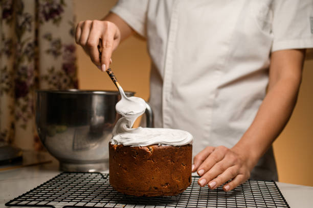 Expert hands decorate the Easter cake, adding a creamy layer of whipped cream.