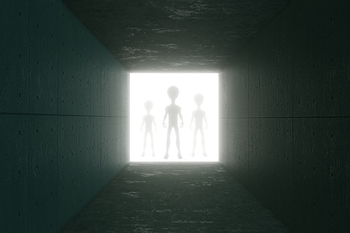 Silhouettes of aliens standing at the end of a tunnel made of concrete plates. Illustration of the concept of extraterrestrial life and creatures