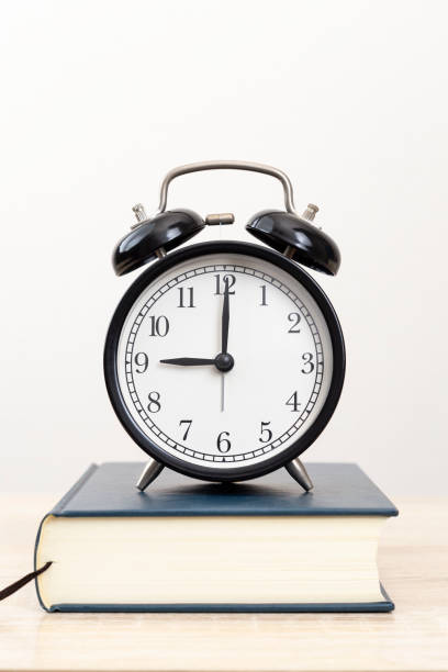 istock A thick book and a clock on the desk. 2052864682