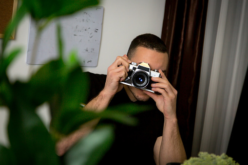A man looks through an old film camera in his office