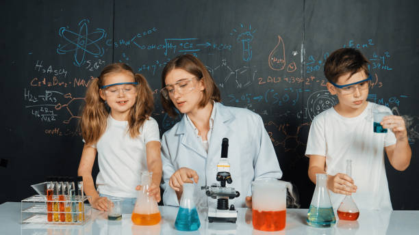 istock Caucasian boy mixing chemical liquid while teacher giving advice. Erudition. 2052883395
