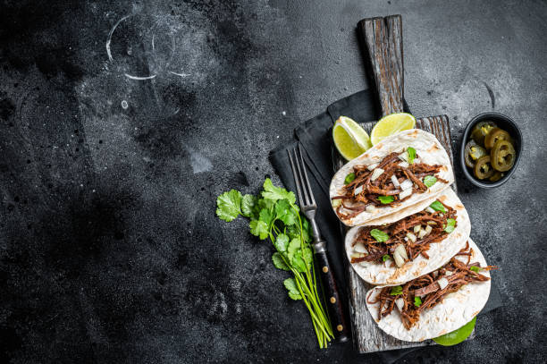 istock Pork carnitas tacos on corn tortillas with onion and lime. Black background. Top view. Copy space 2052890821