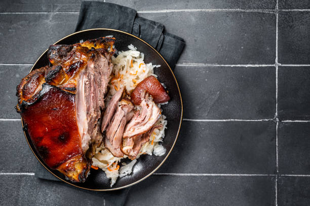 istock Roast Pork Ham Hock, knuckle with Sauerkraut on a plate. Black background. Top view. Copy space 2052890859