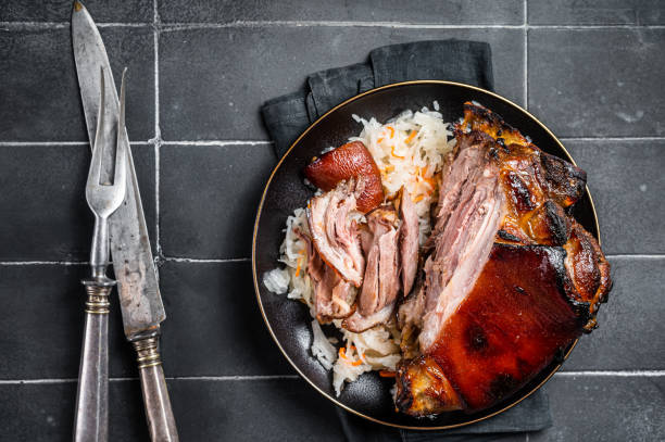istock Roast Pork Ham Hock, knuckle with Sauerkraut on a plate. Black background. Top view 2052890863
