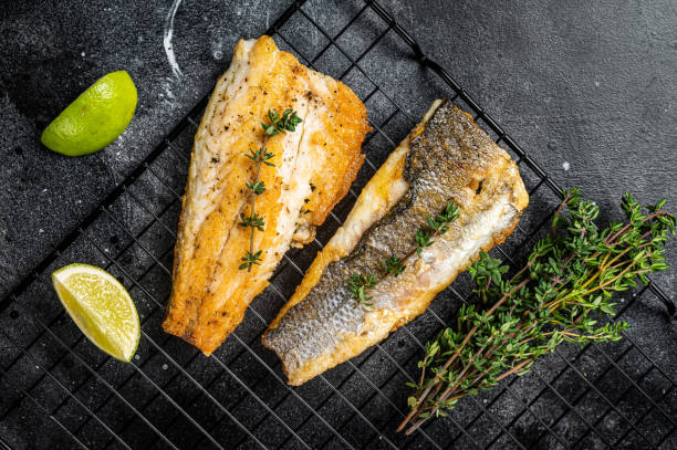 grilled sea bass fillet with lime and thyme. black background. top view - labrax стоковые фото и изображения