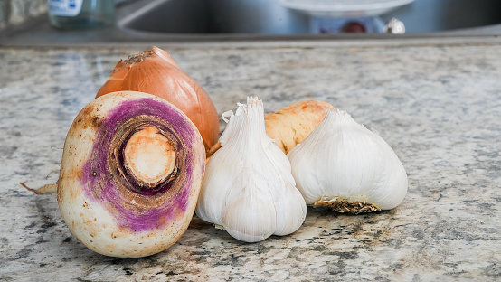 Close up from two garlic,  parsley, onion and white turnip resting on kitchen counter