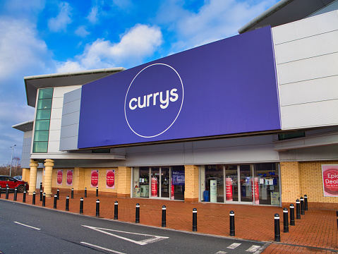 St Helens, UK - Jan 4 2024: Corporate signage and the customer entrance at a Currys superstore in St Helens, Merseyside, England, UK. The company was branded Currys PC World between 2010 and 2021.