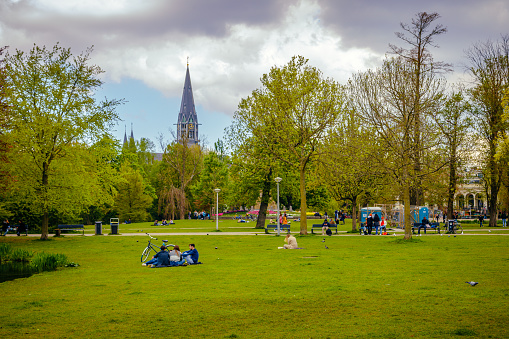 Amsterdam, Netherlands - April 26, 2022: People enjoying and relaxing in Vondel Park on a sunny day. The Vondelpark is biggest public urban park of 47 hectares in Amsterdam, Netherlands.