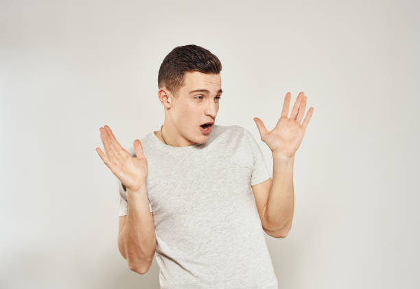 istock Cheerful handsome man in T-shirt emotions gestures with hands light background 2052981605