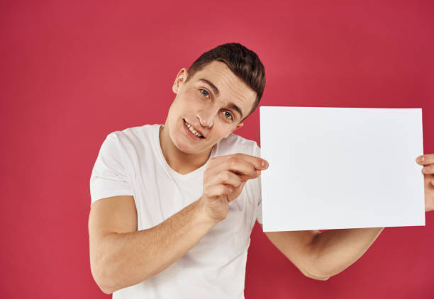 istock Man with a flyer in his hand on a red background advertising mockup Copy Space 2052987070