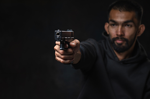 Portrait of a SWAT team soldier standing outdoors and aiming with a handgun.