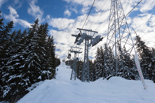 one skier on a chair lift going up mountain in winter