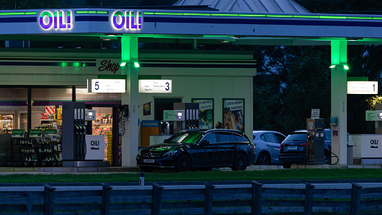 Austria, Tyrol, Zillertal, Uderns, August 8th 2023, nighttime side view close-up of an Austrian black Mercedes station wagon (from the Schwaz district) and other cars being refuelled at the \