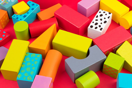 Top view of colorful wooden bricks on the table. Early learning. Educational toys on a red background. For the development of the child.