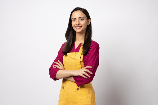 Portrait of young woman chef wearing yellow apron isolated white color background