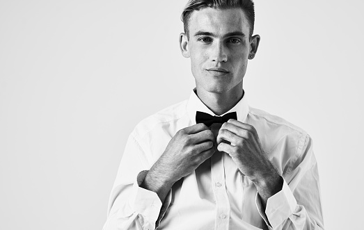 Handsome guy in shirt and bow tie on light background portrait cropped view. High quality photo