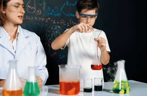 istock Teacher support student experiment liquid in tube in laboratory. Erudition. 2053100090