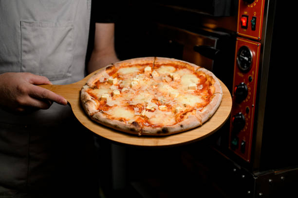 istock Chef taking fresh cheese pizza out of the oven. 2053141180