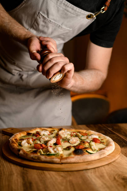istock Chef final touch. Sprinkling seasonings on finished pizza 2053146453
