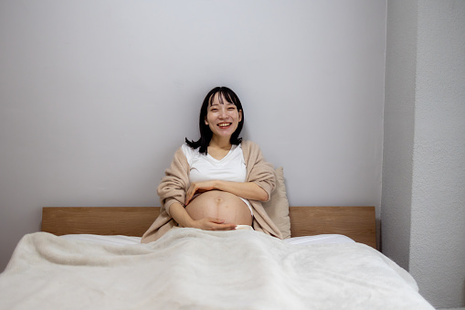 Portrait of happy maternity woman in bed in the morning