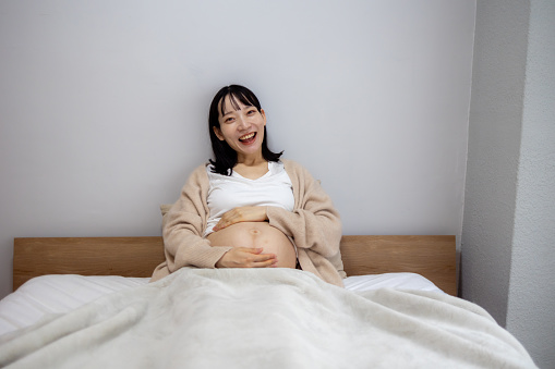 Portrait of happy maternity woman in bed in the morning