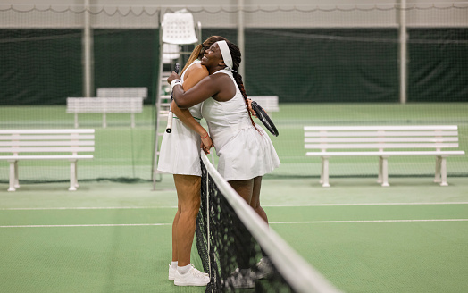 Multiracial female tennis players hugging after friendly match. Sport and healthy lifestyle concept.