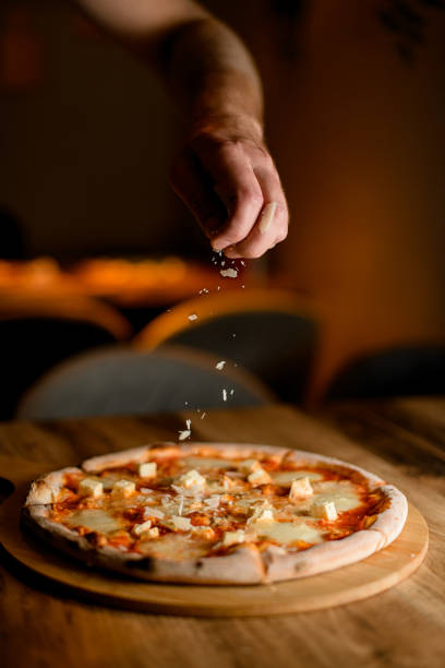 istock Chef culinary finale. Sprinkling cheese on finished pizza. 2053167750