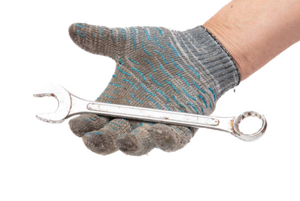 Hands in work gloves holding a wrench, isolated on white background.