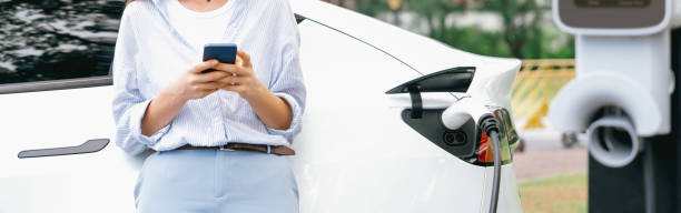 istock Young woman using smartphone to pay for electric car charging. Exalt 2053179526