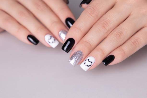 istock Female hands with black manicure nails, hearts design 2053192329