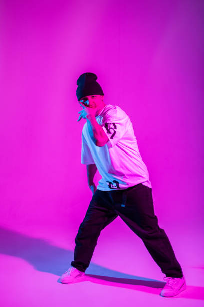 istock Handsome cool professional breakdancer guy in trendy clothes dancing in bright color studio with pink and neon lights 2053207505