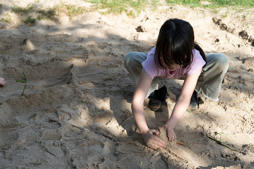 A girl enjoys digging in the sand on a Summer afternoon.