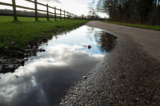 Focus of a large puddle of water after a heavy storm in the UK. The partial cloudscape is visible in the reflection.