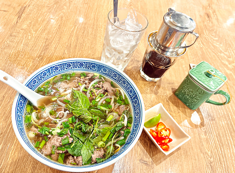 Pho is a Vietnamese soup dish consisting of broth, rice noodles, herbs, and meat. Phở is a popular food in Vietnam where it is served in households, street-stalls, and restaurants country-wide.\nVietnamese iced coffee is a traditional Vietnamese coffee recipe. It is created using coffee roasted between medium and dark. The drink is made by passing hot water through the grounds into a cup that already contains condensed milk.