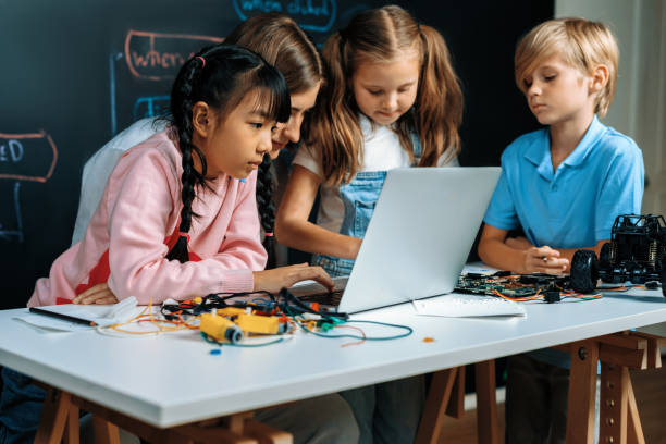 istock Girl wear pink cloth use laptop for coding while teacher watch her. Erudition. 2053254296