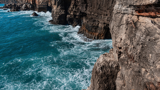 Amazing Atlantic Ocean with waves near the mountain. Journey to Portugal. Blue sea water with waves near rock. Beautiful island in the ocean.