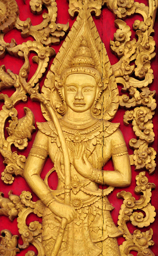 : intricately carved wooden door with golden representation of a Gandharva, a male celestial musician,  in Hinduism, they are regarded to be the celestial demigods who serve as the musicians of the devas, while in Buddhism they are in an intermediate state (between death and rebirth)
